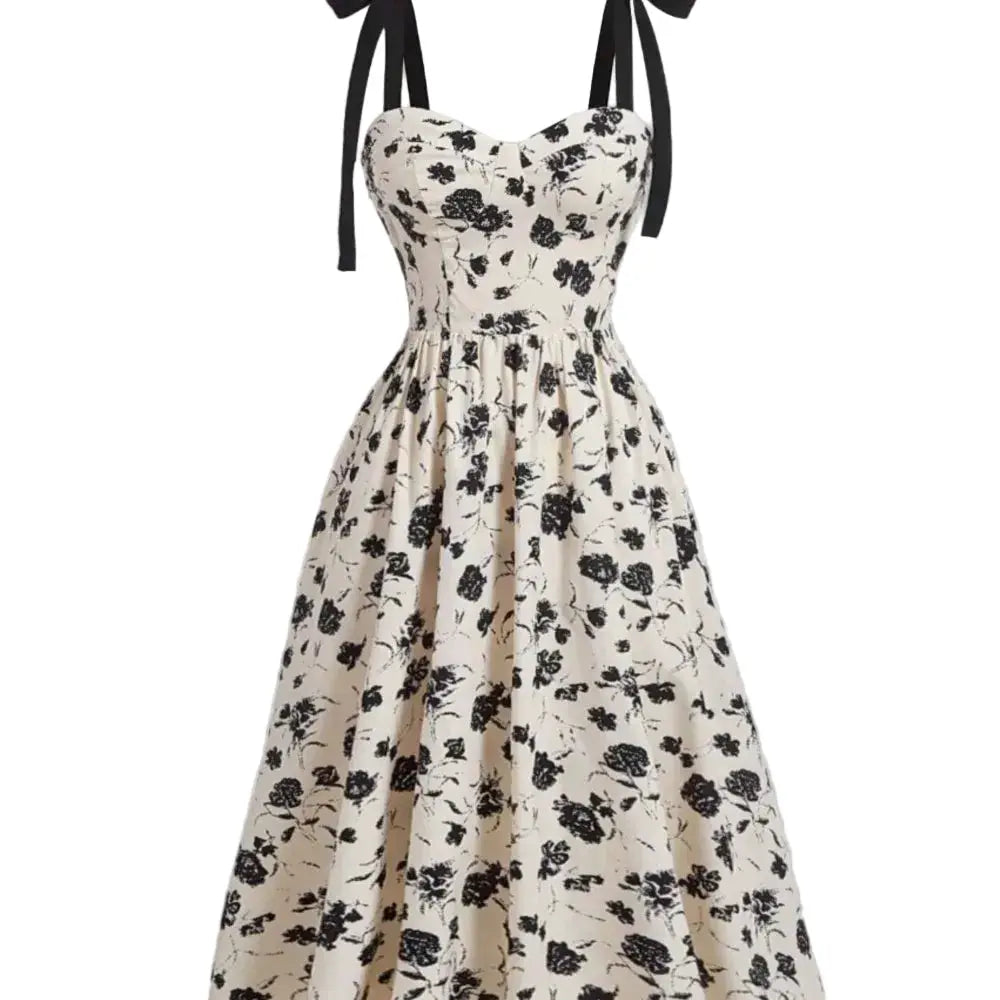 Robe mi-mollet à bretelles fines, imprimé floral noir sur crème, silhouette évasée.