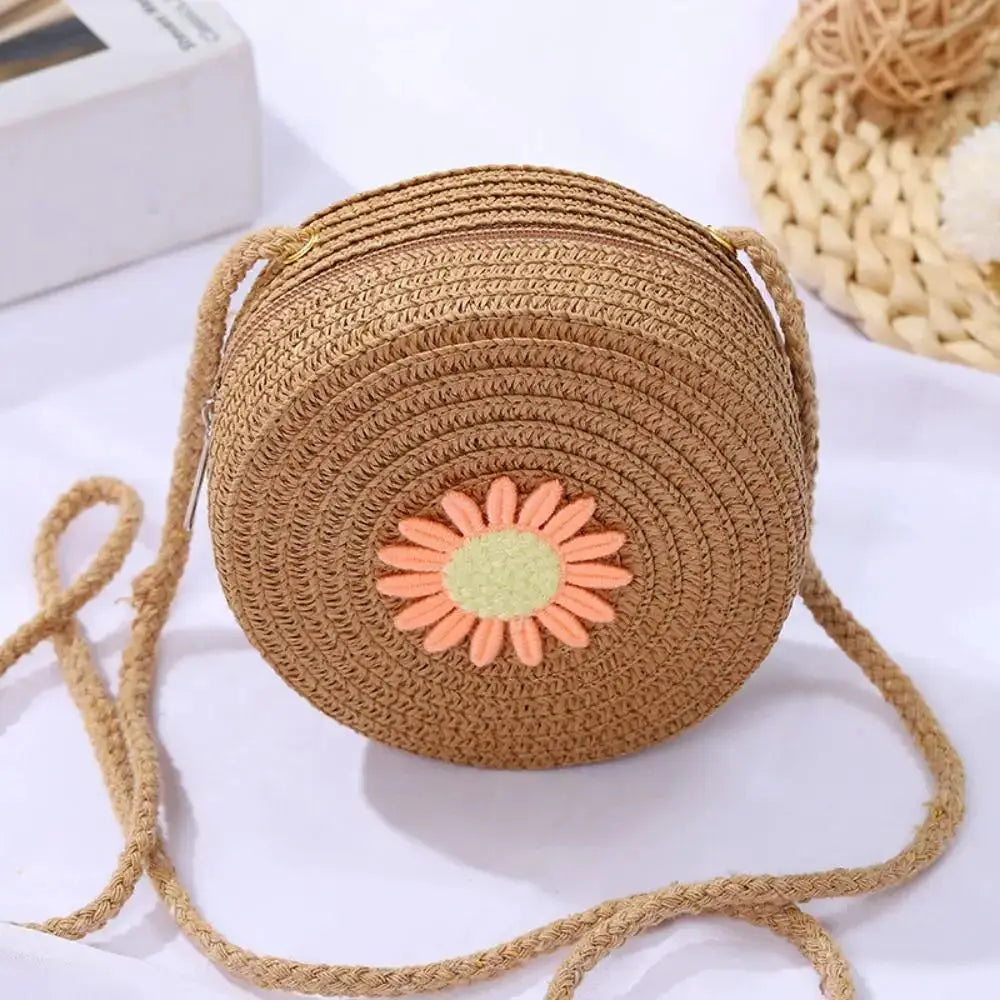Sac rond en rotin naturel avec bandoulière; fleur décorative orange pâle et centre vert clair.