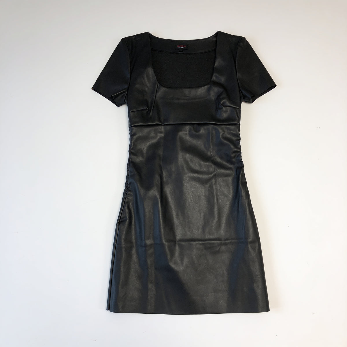 Robe courte en simili cuir noire présentée à plat sur fond blanc